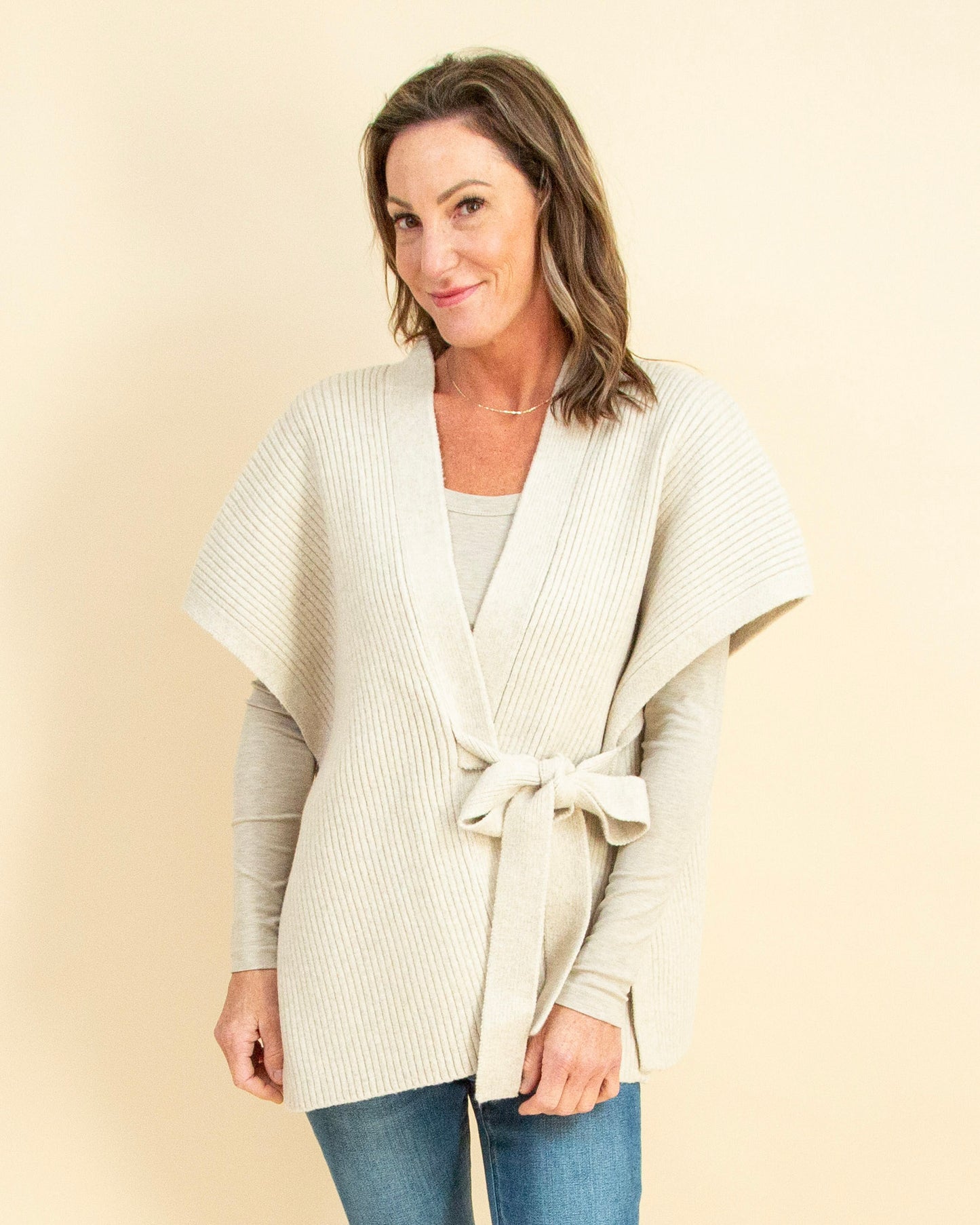 Woman wearing a cream-colored cardigan against a beige background